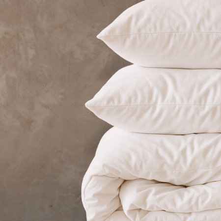 Stack of white pillows and duvet on a beige background