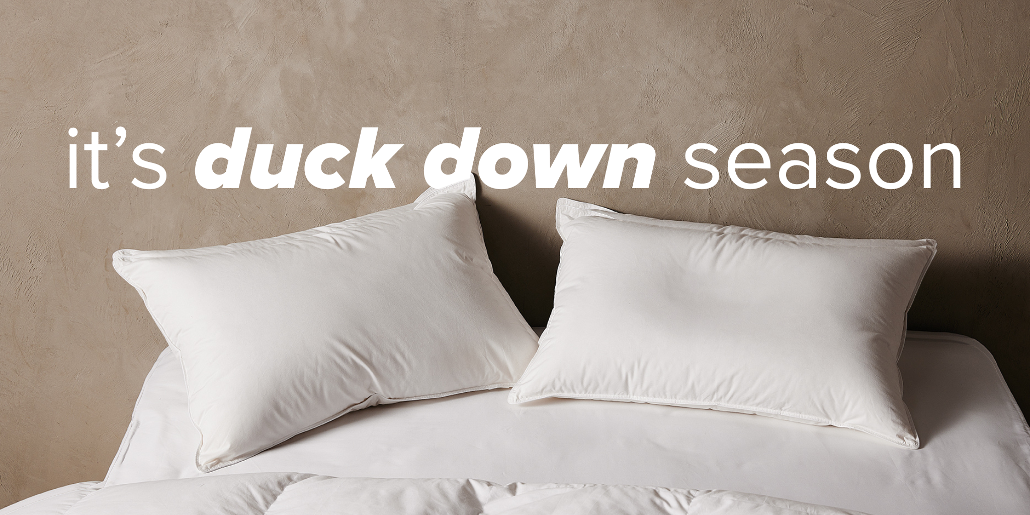 Two white pillows on a bed with 'it's duck down season' text.