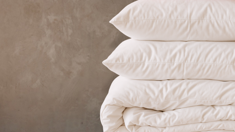 Stack of white pillows and duvet on a beige background